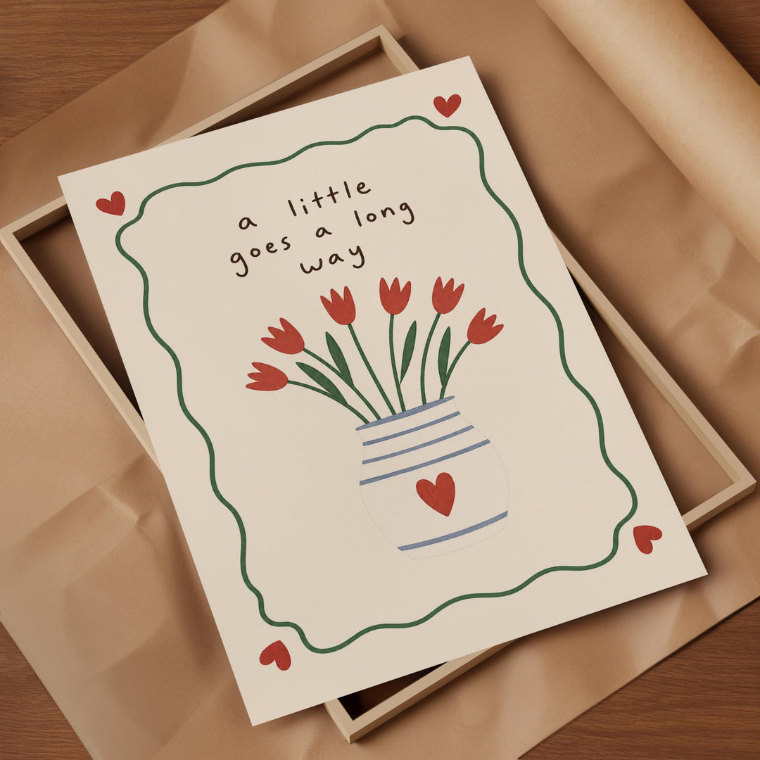 A greeting card with a vase of red flowers and the text "a little goes a long way" written on it.