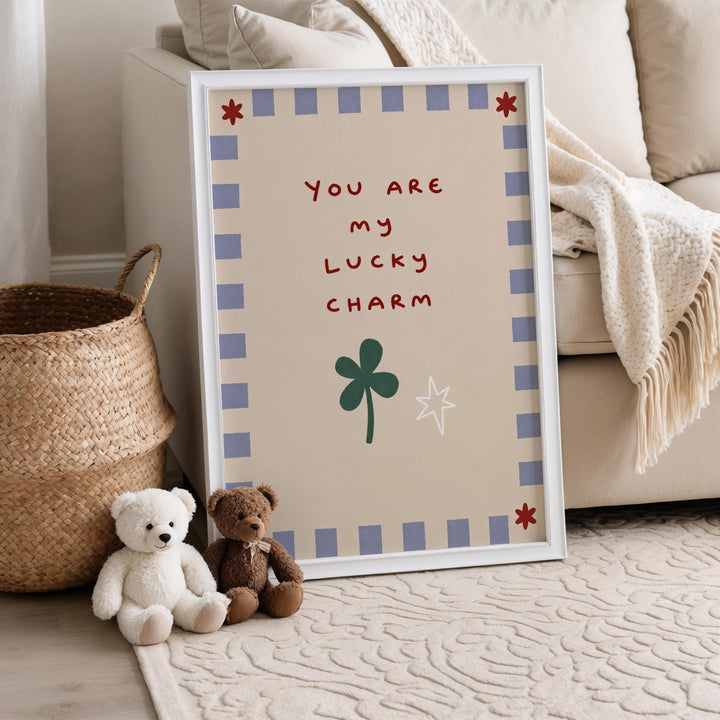 A framed sign with a message that reads "You are my lucky charm" is displayed on a beige couch, with two teddy bears sitting next to it.