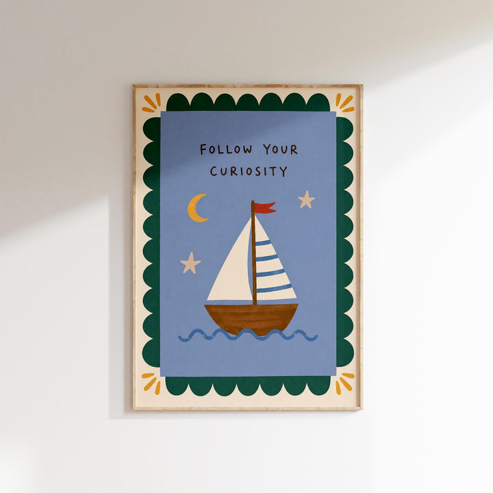 The image is a framed artwork depicting a sailboat on a blue background with a scalloped border and stars. The text "Follow Your Curiosity" is written above the sailboat.