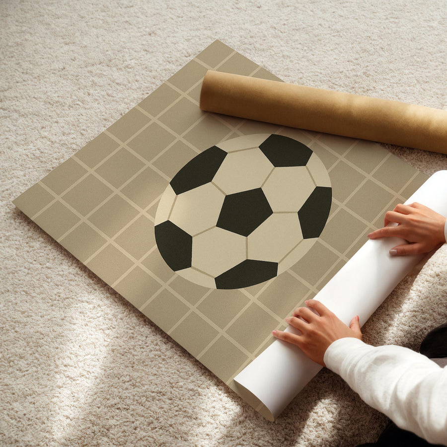 a person laying on the floor next to a roll of paper with a soccer ball