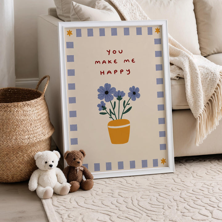 A framed poster with a floral design and the text "You make me happy" is displayed on a wall, accompanied by two teddy bears sitting on the floor next to it.