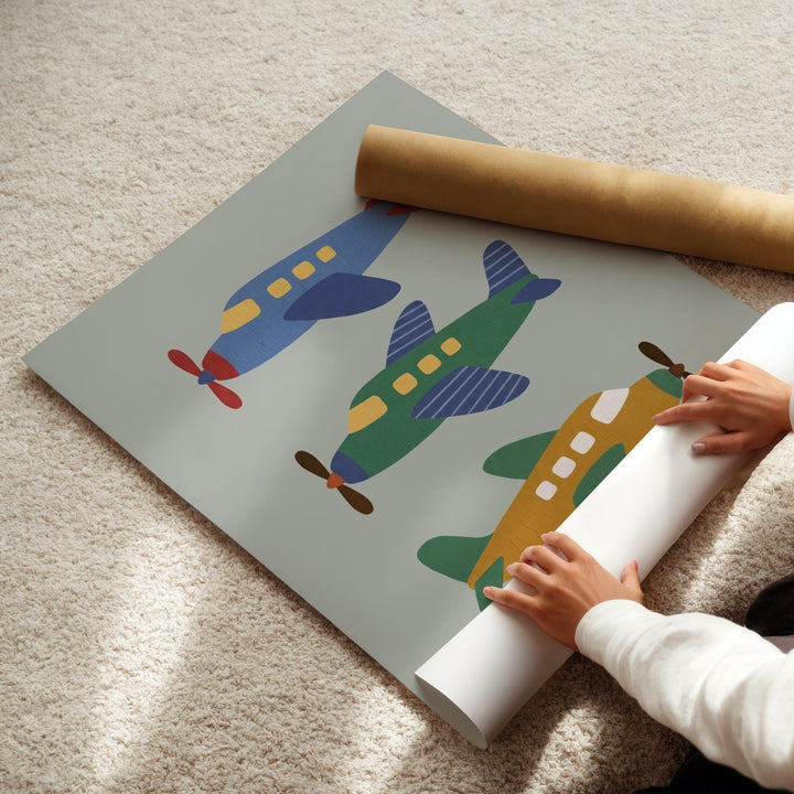 A child's hands are holding a roll of paper, which appears to be a piece of paper with a colorful airplane design printed on it.