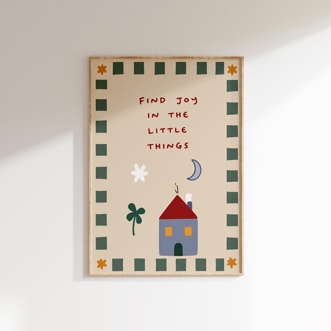 The image is a framed poster with a cheerful and whimsical design. It features a house, flowers, and a crescent moon, all set against a light brown background. The text on the poster reads "Find Joy in the Little Things", which appears to be a message or quote about finding happiness in everyday moments.