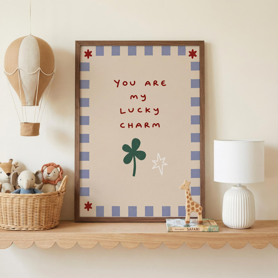 a shelf with a framed picture, a lamp, a basket of stuffed animals, and a toy giraffe. The framed picture has a message that reads "You are my lucky charm".