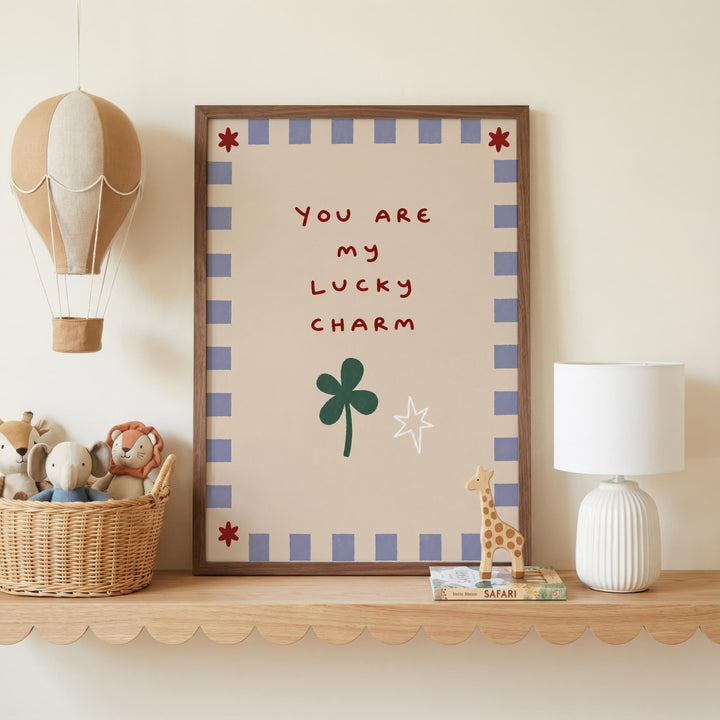 a shelf with a framed picture, a lamp, a basket of stuffed animals, and a toy giraffe. The framed picture has a message that reads "You are my lucky charm".