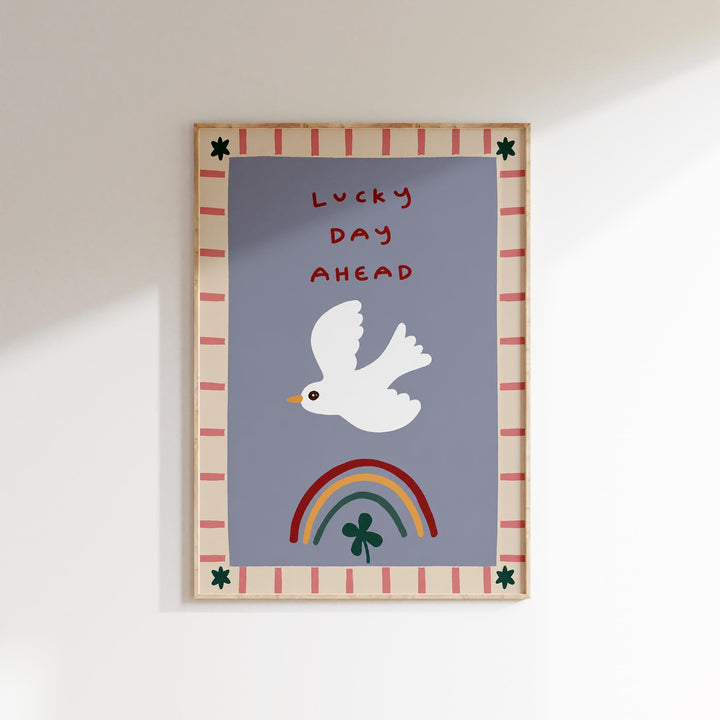 The image is a framed poster with a white bird, a rainbow, and a clover. The text on the poster says "Lucky Day Ahead".