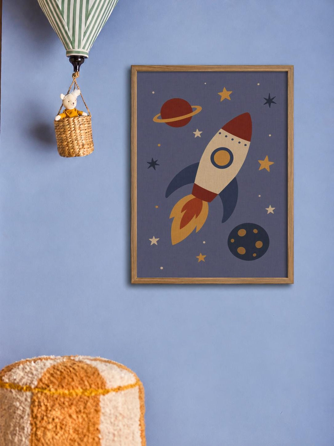 a framed picture of a rocket ship with planets and stars on a blue background, hanging on a wall.