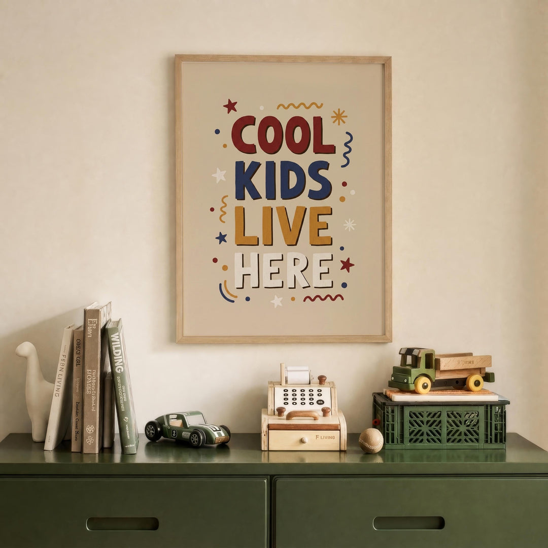 a framed poster with the text "COOL KIDS LIVE HERE" hanging on a wall above a green dresser with various items on it, including books, toys, and a toy cash register.