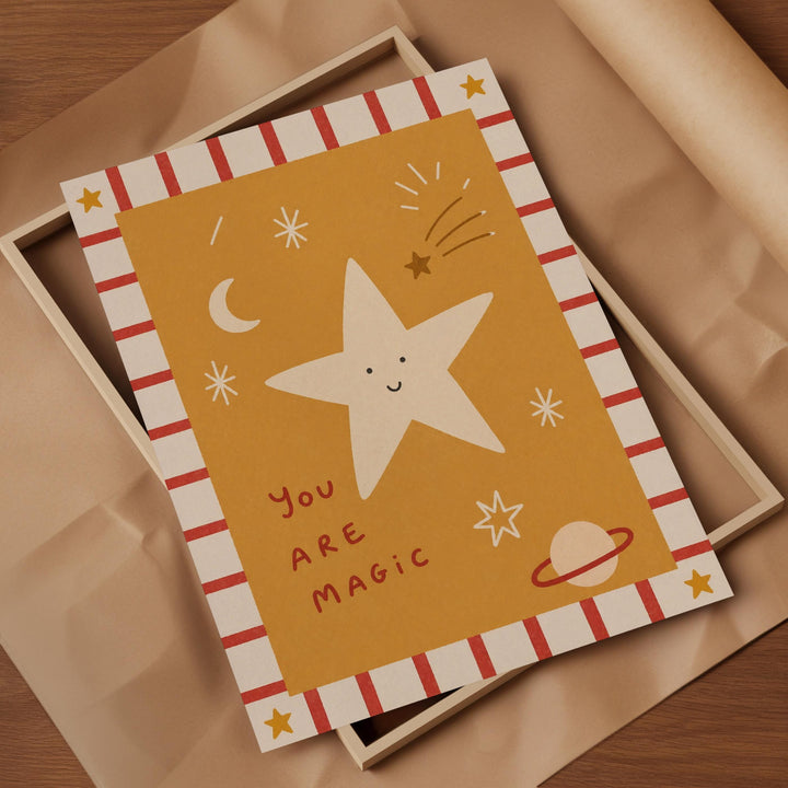 a card with a star and various celestial elements, such as a crescent moon, stars, and a planet, all set against a yellow background. The card has a playful and whimsical design, with the phrase "You are magical" written on it.
